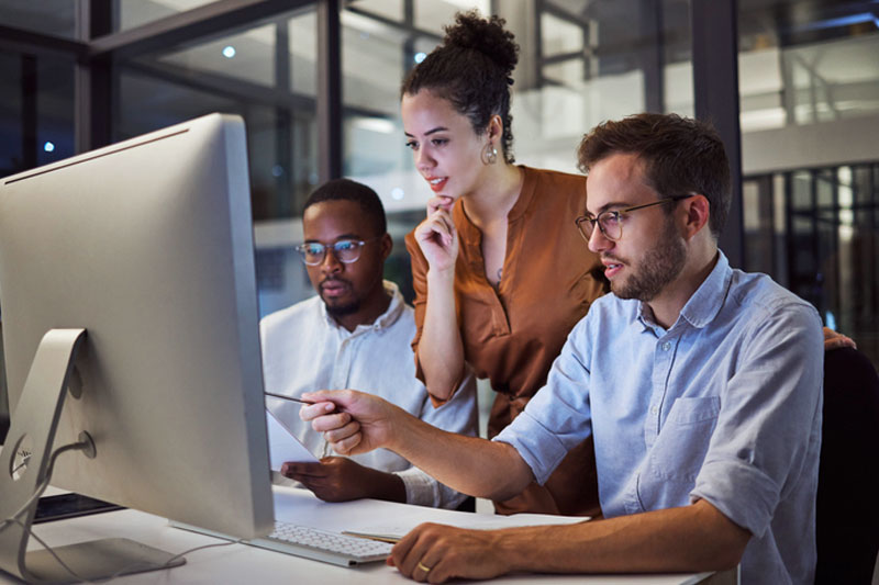 Colleagues looking at computer and pointing with pencil.