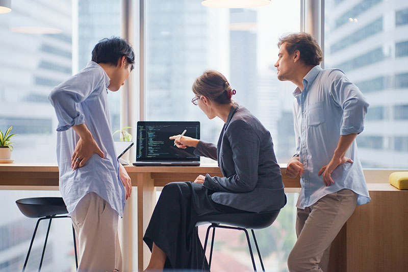 Employees are watching a laptop content in the company building hallway together.