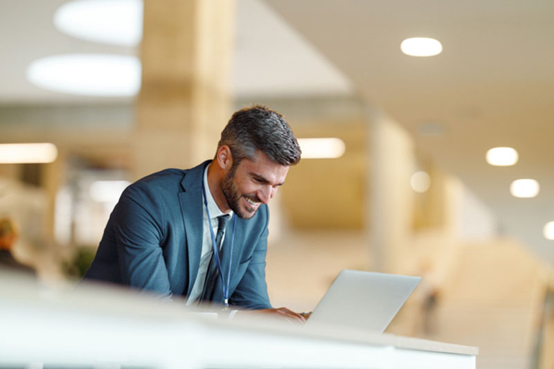Happy businessman talking to female colleague while using laptop in convention center.